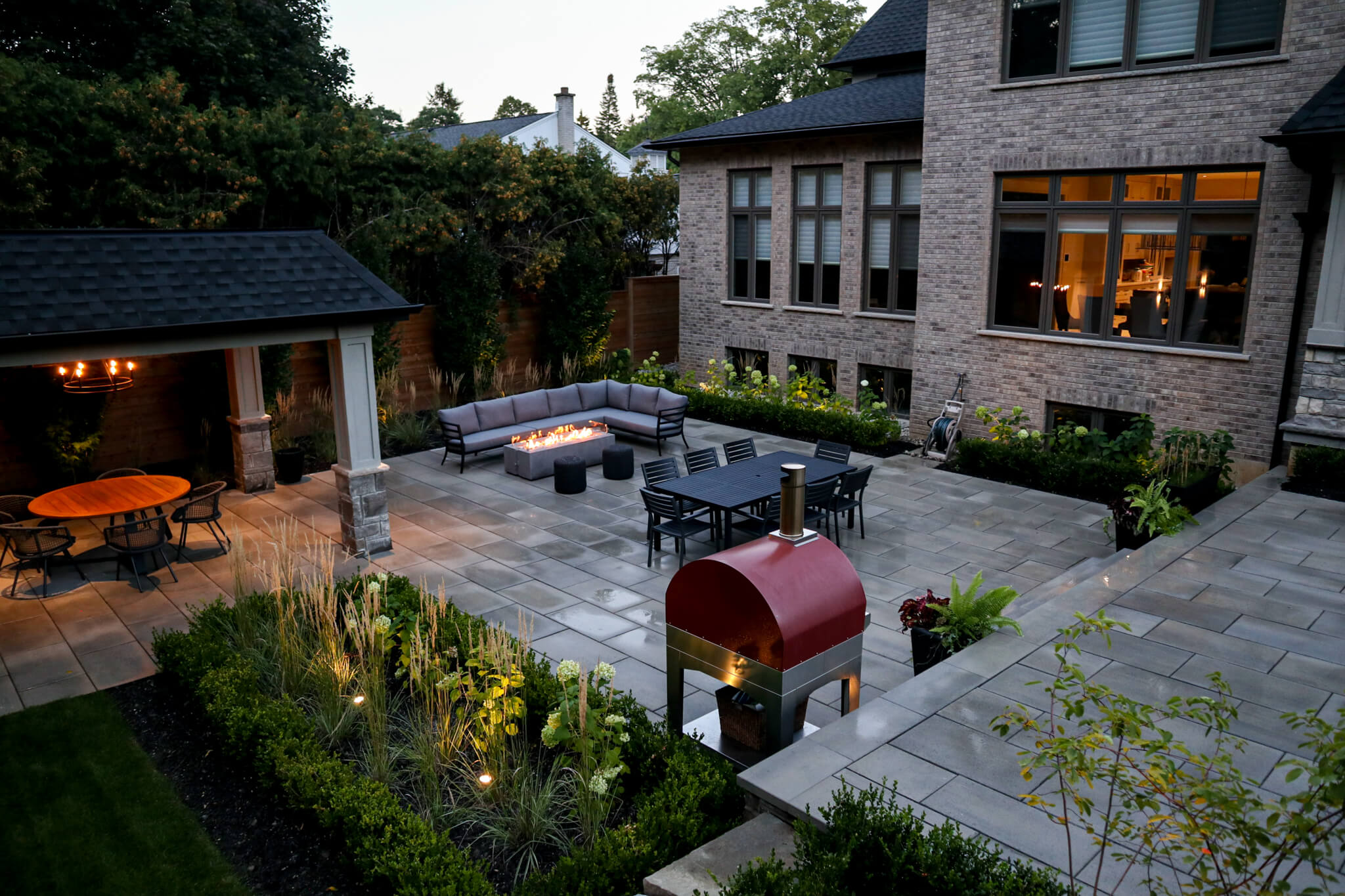 Residential landscaping project in Hamilton – large outdoor living space with fire table, sheltered patio, and pizza oven