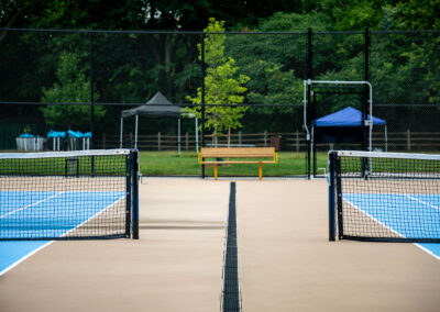 Beige and blue tennis courts with yellow player benches