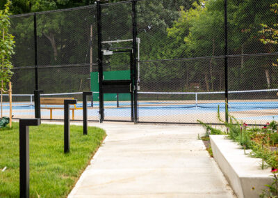 Walkway with concrete benches that lead to tennis court and ambient lighting