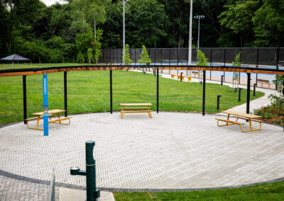 Large circular seating area with yellow park benches and a shade structure