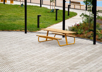 Yellow picnic table in a large circular gathering area under a shade structure