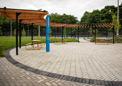 Brown and black shade structure with yellow picnic tables