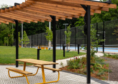 Brown wood and black metal shade structure with a yellow picnic table