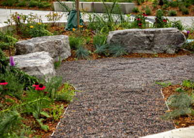 Garden with vibrant flowers, gravel stone pathway, and armour stone for seating