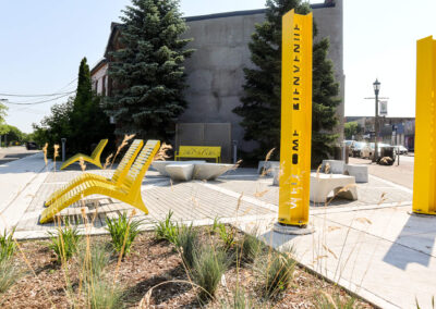 Yellow metal seating area with benches and lounge chairs with a garden