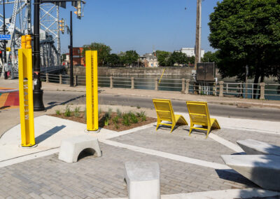 Yellow metal lounge chairs and concrete stools in the Welland Parkette overlooking the canal