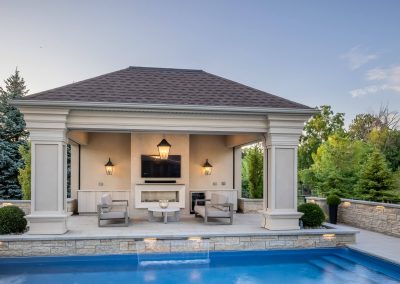 An open-air poolside cabana designed for relaxed entertaining, featuring integrated lighting, lounge seating, and a seamless connection to the surrounding pool and patio.