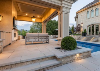 An open-air cabana lounge designed for relaxed poolside living, featuring integrated lighting, built-in millwork, and seamless flow between seating, water, and landscape.