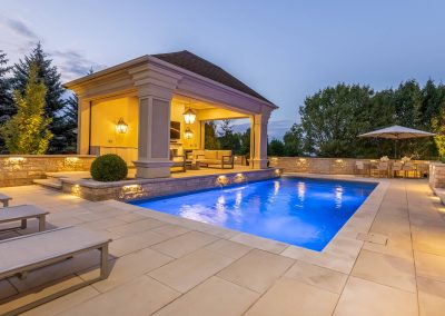 A poolside pavilion paired with stone hardscaping and integrated lighting creates a balanced outdoor space designed for comfort, flow, and evening use.