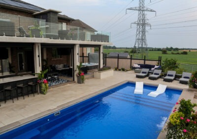 Stone planter with cascading greenery beside a blue pool, with Banas rockface coping on multi-level steps.