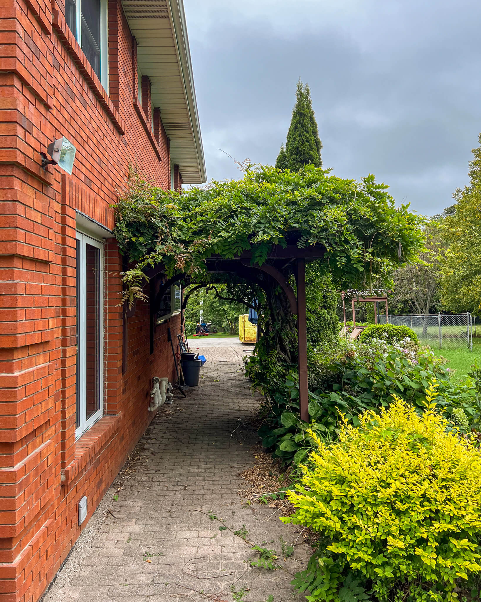 Front view of a brick home before landscaping improvements, showing lawn and existing foundation plantings prior to the Project Mountsberg renovation.